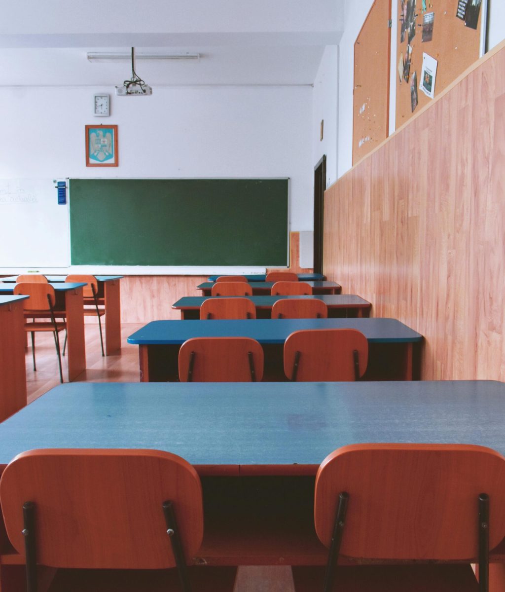 A tranquil empty classroom with wooden furniture and a green chalkboard, perfect for educational themes.