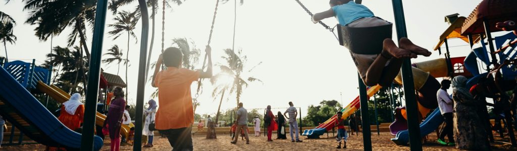 Kids swinging and enjoying a fun day at a tropical playground.